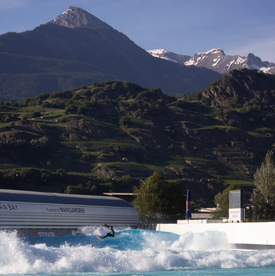 Surfing an artificial wave with the Alps in the background